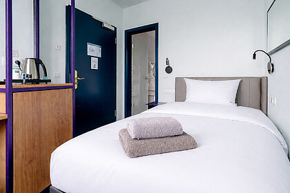 Economy Einzelzimmer im Hotel Schreder München – gemütliches Bett und stilvolle Einrichtung für eine günstige Übernachtung